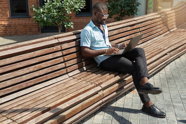 retrato de bonito jovem africano de óculos com laptop