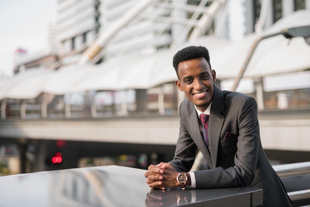 Retrato de bonito jovem empresário africano ao ar livre na cidade