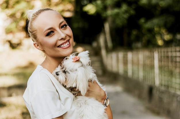 Retrato, de, bonito, mulher sorridente, segurando, maltês, cão