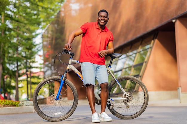 Retrato de bonito sorridente elegante hipster com bicicleta no parque