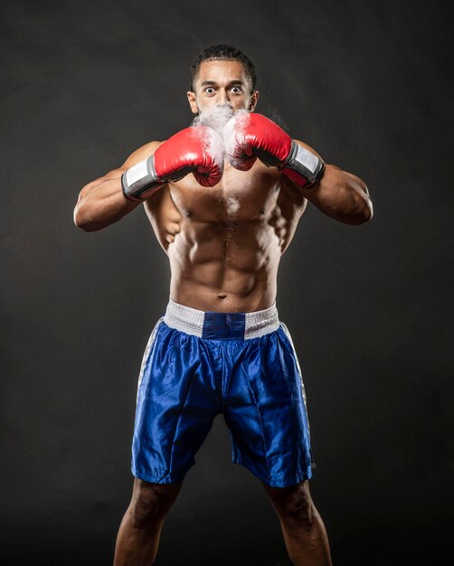 Foto retrato de boxeador sem camisa de pé contra fundo preto