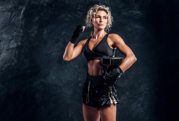 Retrato de boxer feminino forte poderoso em luvas vermelhas sobre fundo escuro.