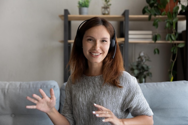 Foto retrato de cabeça de mulher sorridente com fones de ouvido falando e olhando para a câmera sentada no sofá em casa professor mentor gravando webinar liderando lição on-line envolvido em reunião na internet
