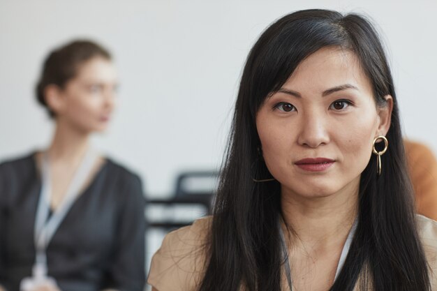 Foto retrato de cabeça e ombros de uma mulher de negócios asiática olhando para a câmera enquanto está sentado na platéia em uma conferência de negócios ou seminário, copie o espaço