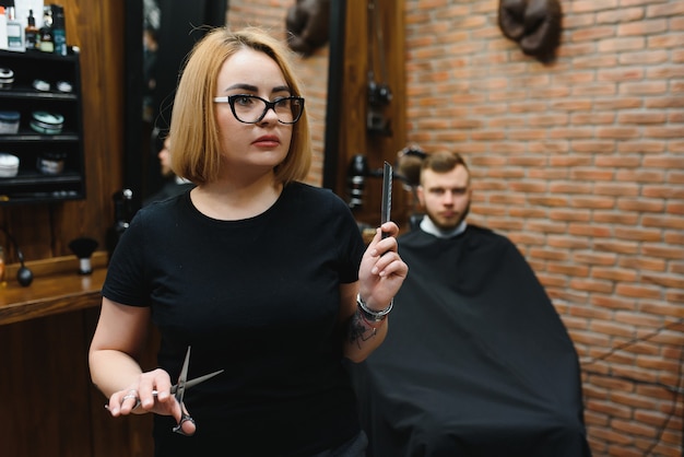 Retrato de cabeleireiro estilista de moda mulher com uma tesoura na mão na barbearia