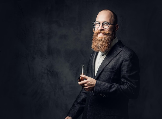 Retrato de cachimbo inglês masculino ruivo barbudo sobre fundo cinza.