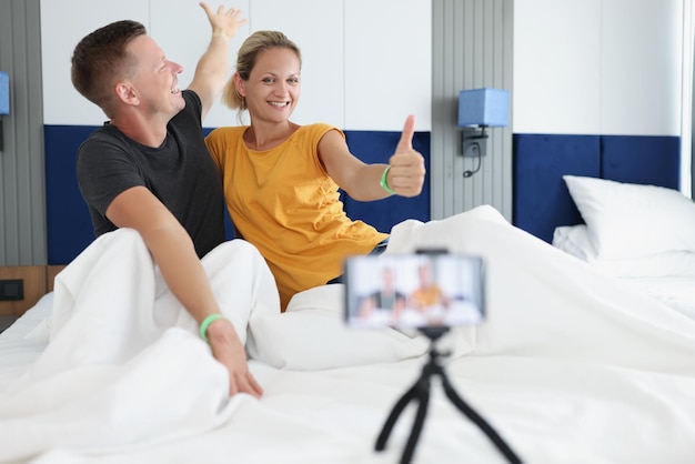 Retrato de casal alegre fazendo fotos no quarto de hotel em uma mulher sorridente ruim aparecendo o polegar