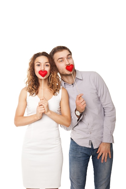 Retrato de casal alegre segurando corações vermelhos e rindo isolado no branco