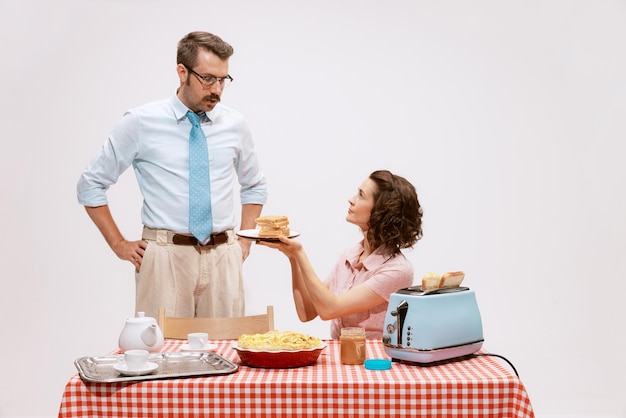 Retrato de casal amoroso, homem e mulher, tomando café da manhã juntos isolados sobre o estúdio branco