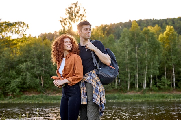 Retrato de casal caucasiano romântico com roupa casual, posando perto do rio na natureza da floresta feliz semana ...