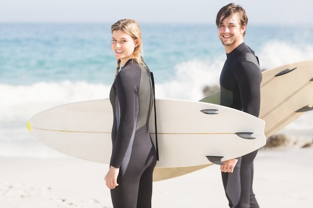 Retrato de casal com pé de prancha de surf na praia