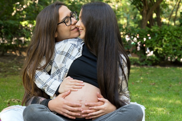 Retrato de casal de lésbicas grávidas afetuosas relaxado no parque duas namoradas felizes livres ...