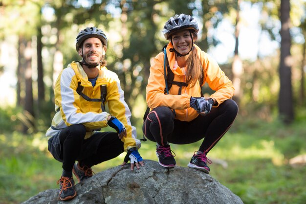 Retrato de casal de motoqueiros sorrindo na floresta