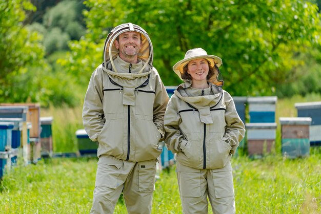 Retrato de casal feliz de apicultores Os apicultores estão trabalhando com abelhas e colméias no apiário durante o posar para a câmera