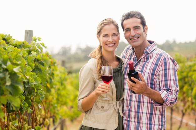 Retrato de casal feliz, segurando o copo e uma garrafa de vinho