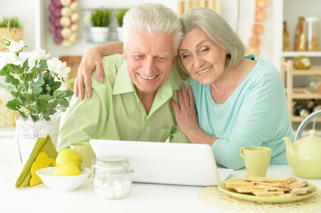 Retrato de casal idoso com laptop em casa