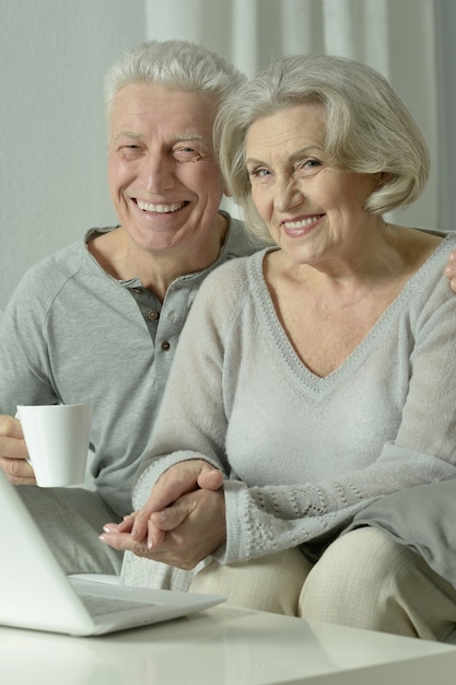 Retrato de casal idoso com laptop em casa