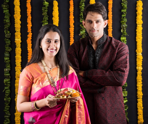 Retrato de casal indiano em trajes tradicionais em Namaskara ou oração, pose de boas-vindas ou puja thali