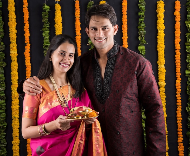 Retrato de casal indiano em trajes tradicionais em Namaskara ou oração, pose de boas-vindas ou puja thali