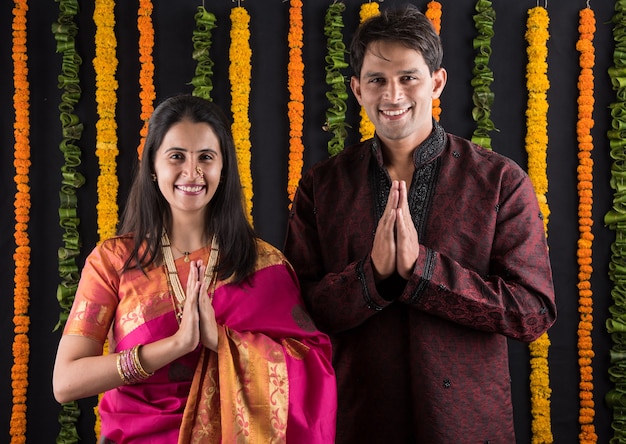 Retrato de casal indiano em trajes tradicionais em Namaskara ou oração, pose de boas-vindas ou puja thali