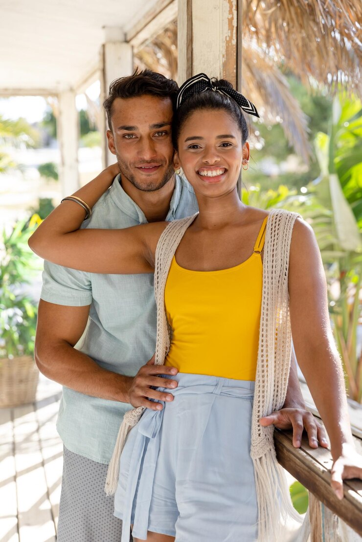 Foto retrato de casal jovem caucasiano romântico sorrindo e parado ao lado da grade na varanda da casa de campo. inalterado, amor, juntos, férias, estância turística, estilo de vida e conceito de diversão.