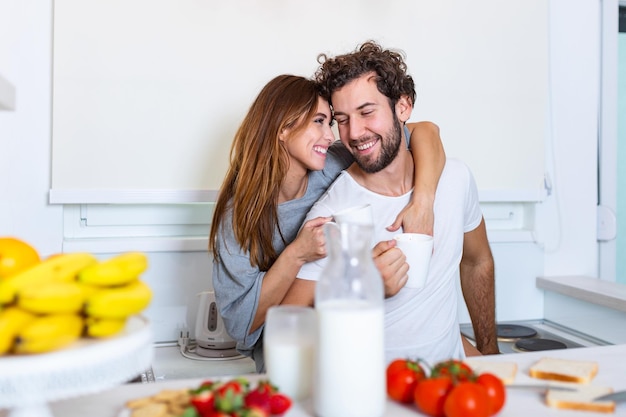 Retrato de casal jovem feliz cozinhando juntos na cozinha em casa. romântico Mulher jovem e atraente e homem bonito estão gostando de passar algum tempo juntos em pé na cozinha moderna leve.