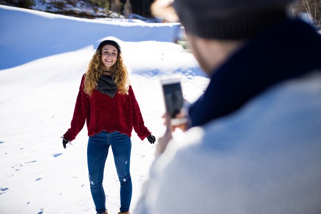 Retrato de casal jovem feliz tirando fotos sobre fundo de inverno.