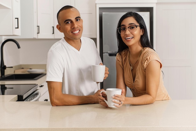 Retrato de casal latino-americano com xícaras na cozinha