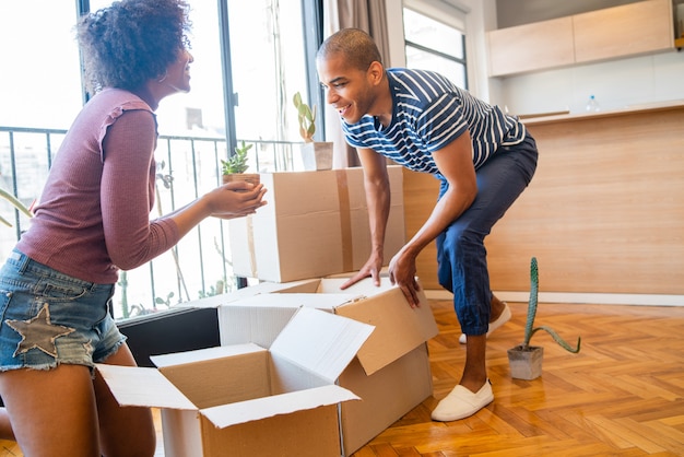 Foto retrato de casal latino feliz, embalagem de caixa de papelão para mudar de apartamento. conceito imobiliário.