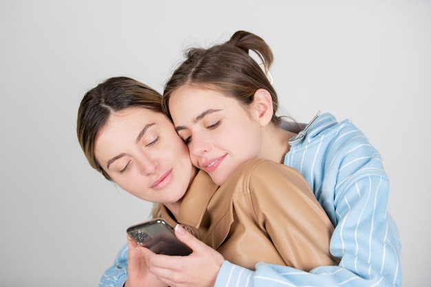 Retrato de casal lgbt de lésbicas de duas jovens alegres com smartphone celular dois lindos