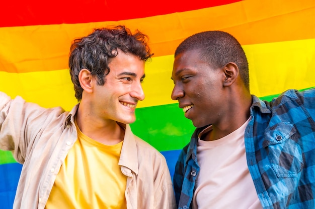 Retrato de casal masculino gay multiétnico segurando uma bandeira de símbolo lgbt de arco-íris