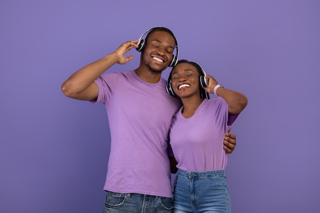 Retrato de casal negro em fones de ouvido abraçando no estúdio