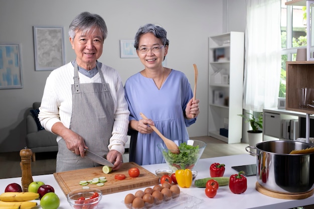 Retrato de casal sênior asiático feliz preparando comida na cozinha Pessoas aposentadas cozinhando em casa olhando para a câmera