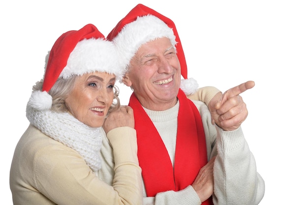 Retrato de casal sênior feliz em chapéus de Papai Noel apontando