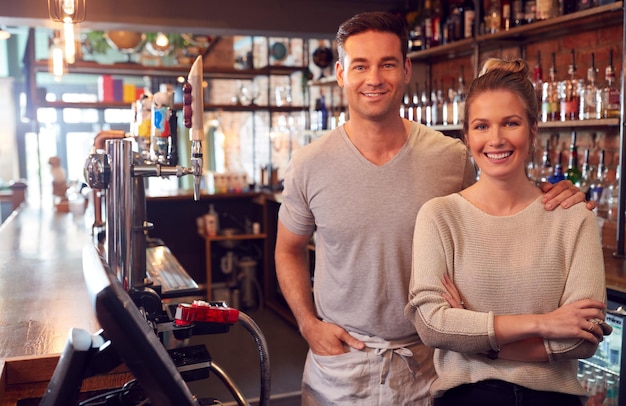 Retrato de casal sorridente dono de bar em pé atrás do balcão