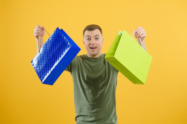 Retrato de casal sorridente segurando sacolas de compras isoladas em fundo amarelo.