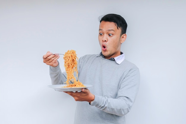 Retrato de Choque e Uau Jovem asiático gosta de macarrão Comendo o conceito de almoço