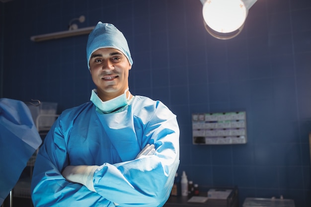 Foto retrato de cirurgião em pé com os braços cruzados na sala de operação