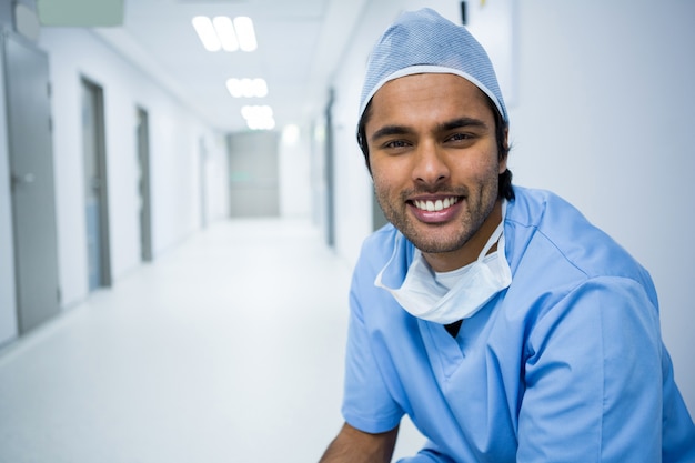 Retrato de cirurgião sorridente, sentado no corredor