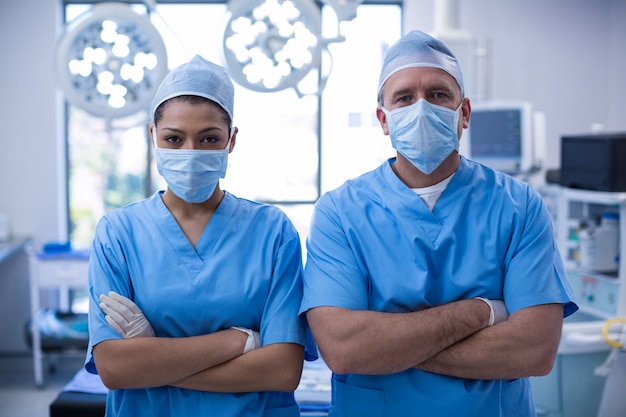 Foto retrato de cirurgiões em pé com os braços cruzados na sala de operação