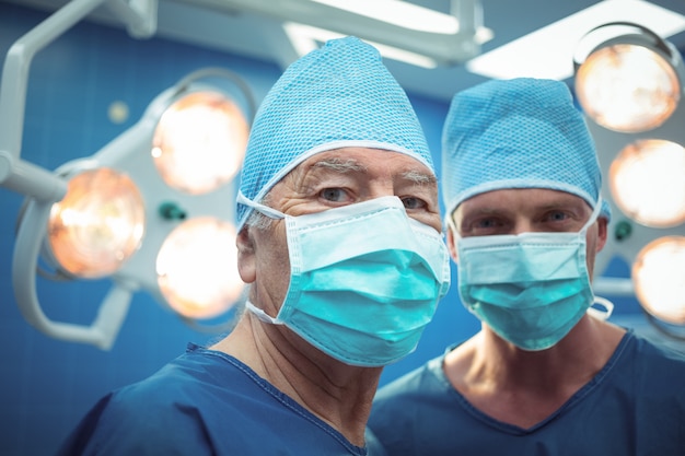 Retrato de cirurgiões masculinos usando máscara cirúrgica no teatro de operação
