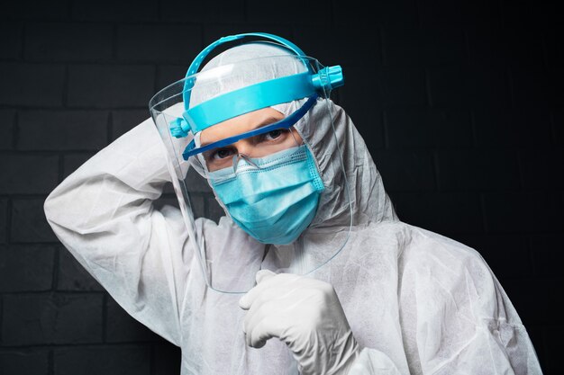 Retrato de close-up de jovem médico vestindo traje de epi contra coronavírus e covid-19