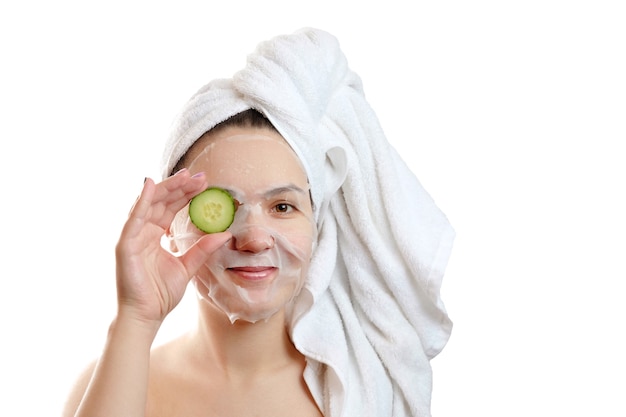 Retrato de close-up de mulher bonita com máscara facial e fatias de pepino nas mãos em fundo branco