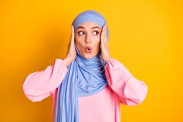 Retrato de close-up de muslimah muito preocupada usando hijab olhando de lado notícias incríveis lábios uau isolado em um fundo de cor amarelo brilhante