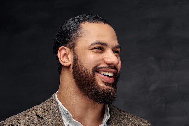 Retrato de close-up de um empresário afro-americano barbudo bonito sorridente em uma jaqueta clássica marrom. Isolado em um fundo escuro.