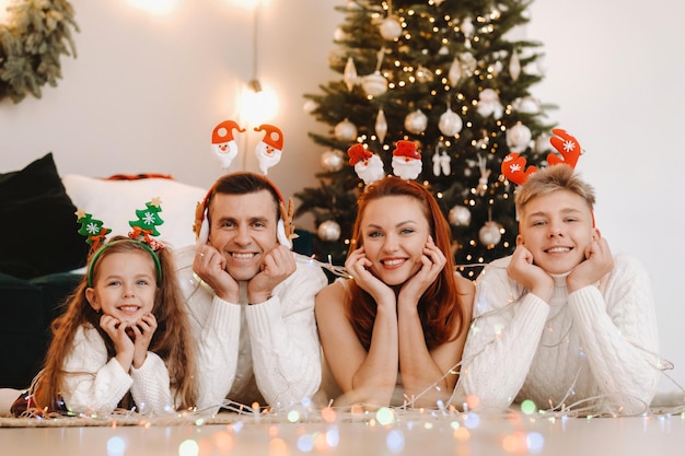Retrato de close-up de uma família feliz deitada perto de uma árvore de Natal, comemorando um feriado