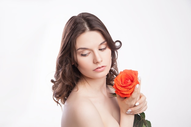 Retrato de close-up de uma linda mulher morena com uma rosa vermelha na mão