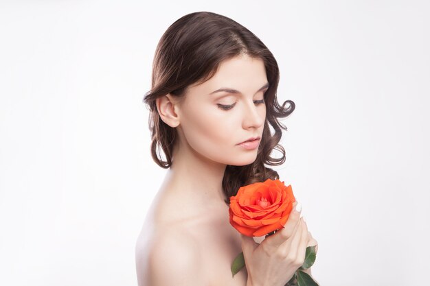 Retrato de close-up de uma linda mulher morena com uma rosa vermelha na mão