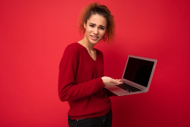 Retrato de close-up de uma linda mulher surpreendida e espantada com uma mulher loira escura segurando um laptop