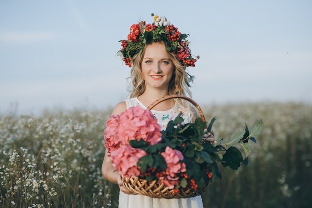 Retrato de close-up de uma menina com uma coroa na cabeça e uma cesta de flores